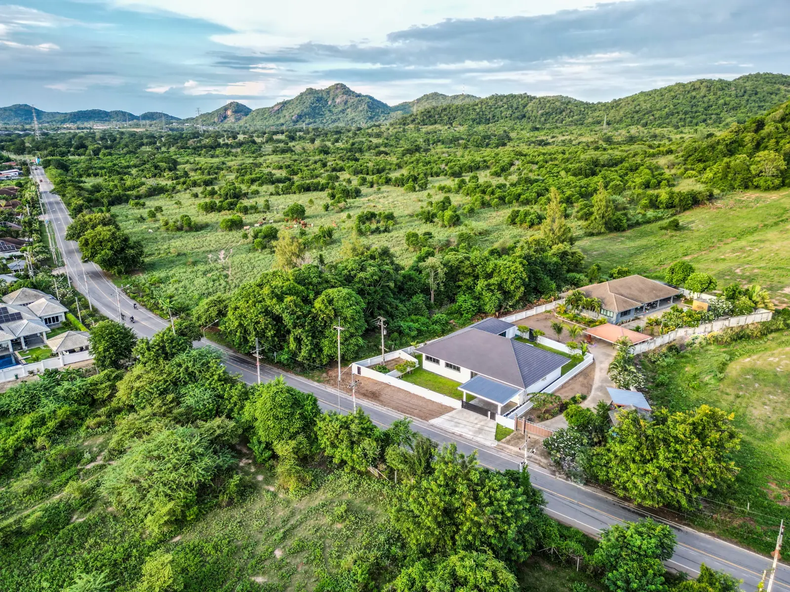 Drone view of the valley with the villa on the road below the mountains